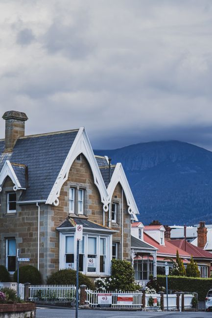 A row of residential houses with varied architectural styles and stone facades, located along a street in Newington. The house in the foreground has a steeply pitched roof with dark slate tiles, decor